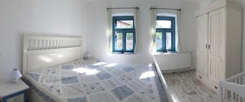 ノスヴァイにあるHűs Udvarの白いベッドルーム(ベッド1台、窓2つ付)