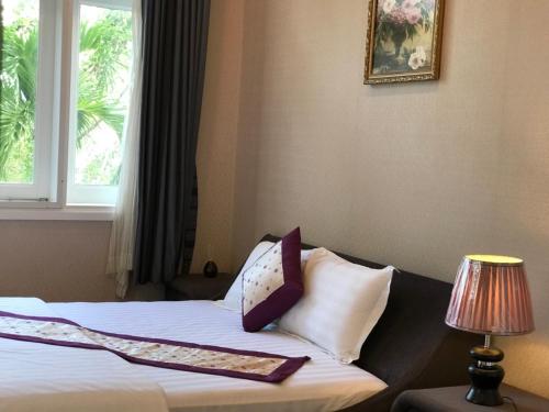 ein Schlafzimmer mit einem Bett mit Kissen und einem Fenster in der Unterkunft Villa Mui Ne Phan Thiet in Mui Ne