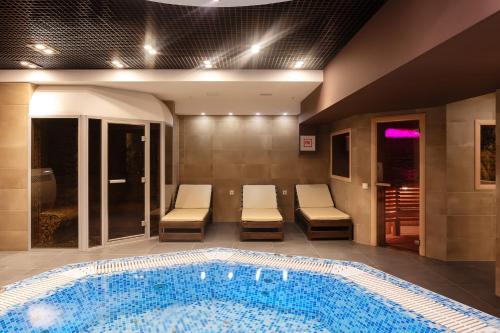 una piscina en una habitación de hotel con 2 sillas en Vega Hotel, en Tolyatti