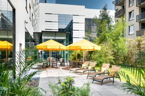 een patio met stoelen en tafels met parasols bij OREA Hotel Angelo Praha in Praag