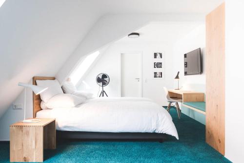 a white bedroom with a bed and a desk at Ulmer Münster Hotel in Ulm