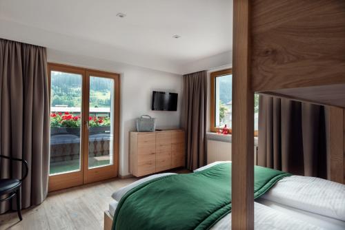 a bedroom with a bed and a large window at ride & relax Aparthotel Schwarz in Eben im Pongau