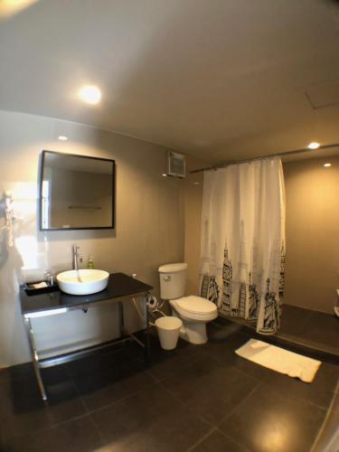 a bathroom with a sink and a toilet and a television at Paragon Inn in Lat Krabang