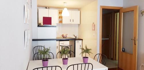 una pequeña cocina con mesa blanca y sillas en Vivienda Turística Pirineos XXI en Canfranc-Estación