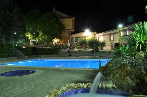 a swimming pool in front of a house at night at La Fuensanta Hostal-Rural in Horche