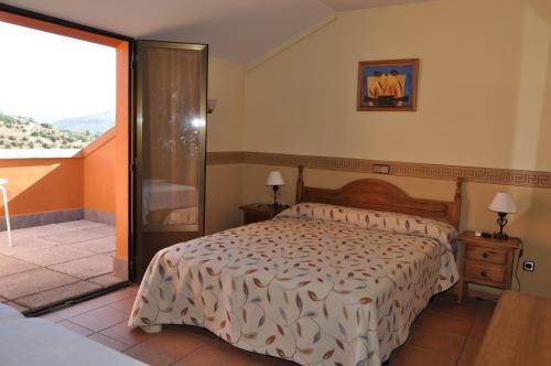 a bedroom with a bed and a balcony at La Fuensanta Hostal-Rural in Horche