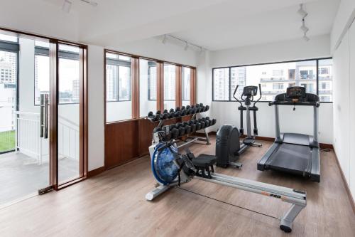 a gym with treadmills and machines in a room with windows at The Kuala Lumpur Journal Hotel in Kuala Lumpur