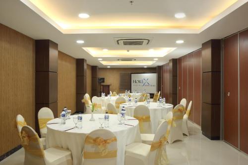 a banquet hall with white tables and chairs and a screen at Horison Express Sentani in Jayapura