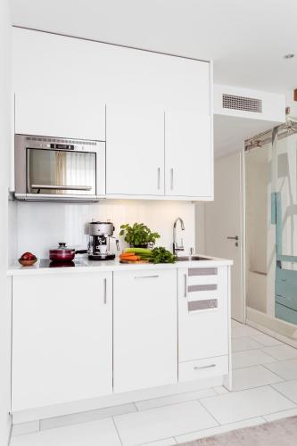 a white kitchen with white cabinets and a sink at Skyreach BizzStay - Wohnen am Main in Frankfurt/Main