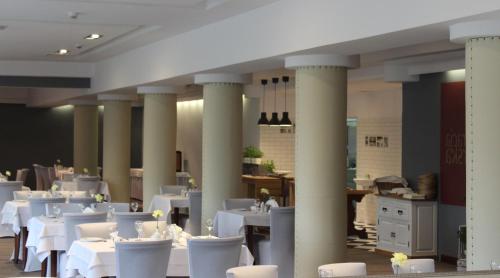un comedor con mesas blancas, sillas y columnas en Hotel Pod Dębem, en Tarnów