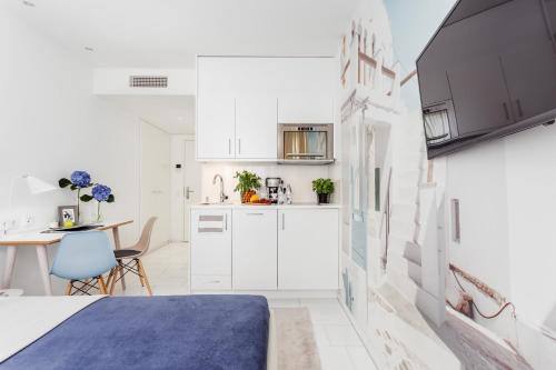 a small kitchen with white cabinets and a table at Skyreach BizzStay - Wohnen am Main in Frankfurt/Main