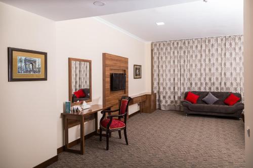 a hotel room with a desk and a couch at Grand Hotel Eurasia in Almaty