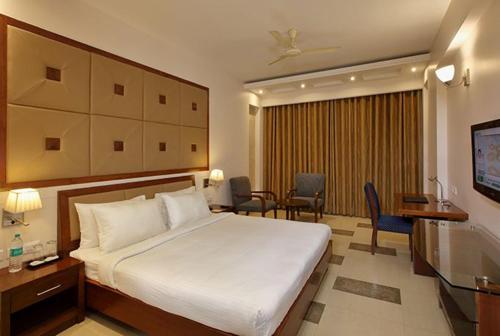 a hotel room with a bed and a table and chairs at Lemon Tree Hotel Baddi in Baddi