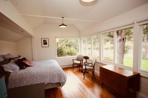 a bedroom with a bed and a table and windows at The Signal Box in Whanganui
