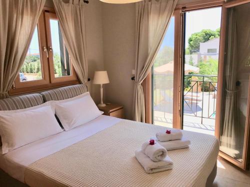 a bedroom with towels on a bed with a balcony at Dolce Vita Villas in Svoronata
