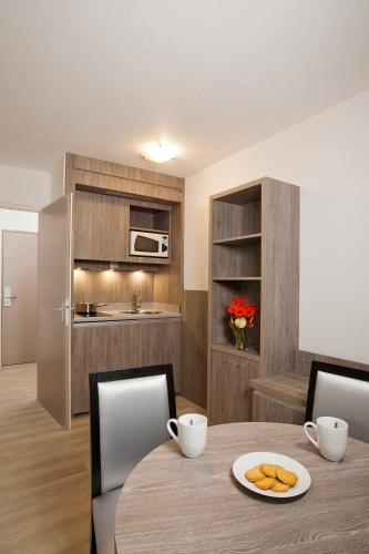a kitchen and dining room with a table and chairs at Séjours & Affaires Reims Clairmarais in Reims