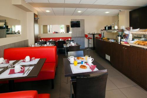 a restaurant with two tables with red chairs and a buffet at Séjours & Affaires Reims Clairmarais in Reims