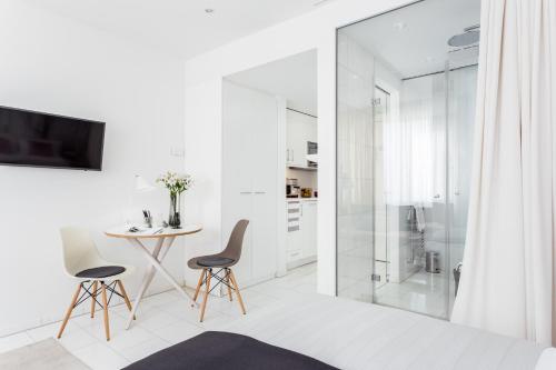 a white bathroom with a glass shower and two chairs and a table at Skyreach BizzStay - Wohnen am Main in Frankfurt/Main