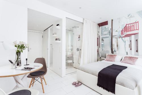 a white bedroom with a bed and a desk and a table at Skyreach BizzStay - Wohnen am Main in Frankfurt/Main