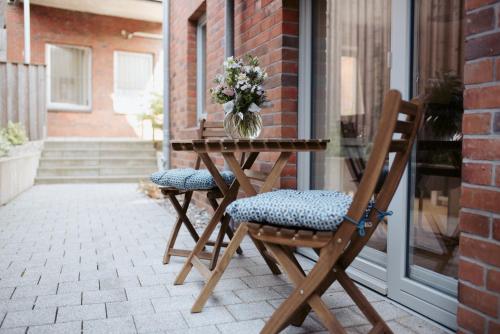a wooden table with two chairs and a vase of flowers at Anker Mal in Husum