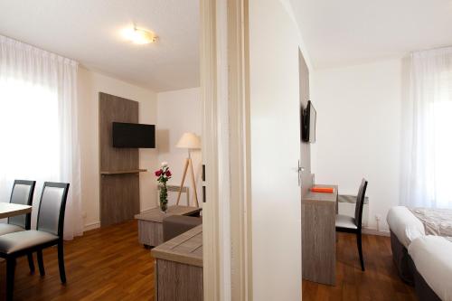 a hotel room with a bed and a table and a desk at Séjours & Affaires Reims Clairmarais in Reims