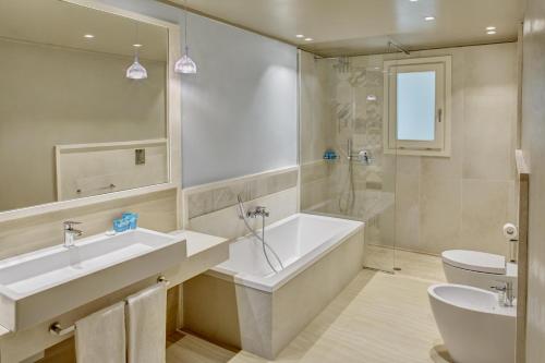 bagno con vasca, lavandino e servizi igienici di Forte Village Resort - Bouganville a Santa Margherita di Pula