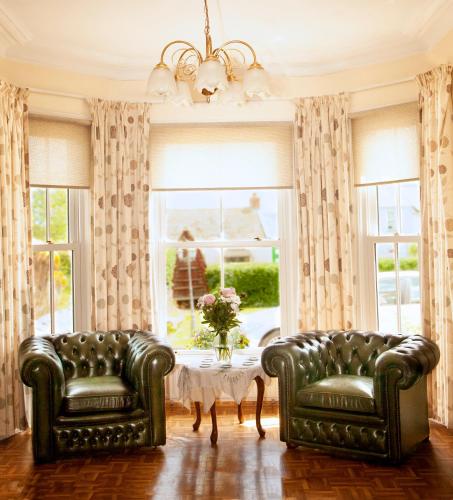 two leather chairs and a table in a room with windows at Burford Lodge Guest House in Ardglass