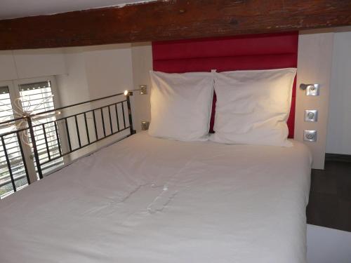 - un grand lit avec des oreillers blancs et une tête de lit rouge dans l'établissement Le 12 Pierres - Croix-Rousse - Cosy & Design, à Lyon
