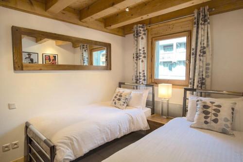 Duas camas num quarto com um espelho e uma janela. em Morgane Apartment em Chamonix-Mont-Blanc