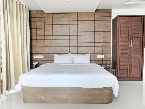a bedroom with a large bed and a tiled wall at Clyford Suites in Bengaluru