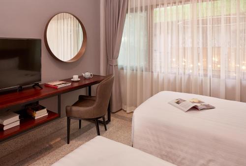 a hotel room with a bed and a desk and a television at W22 by Burasari - SHA Extra Plus Certified in Bangkok