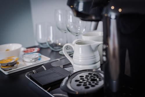 a kitchen counter with a sink with a tea kettle and glasses at Lymm Boutique Rooms in Lymm