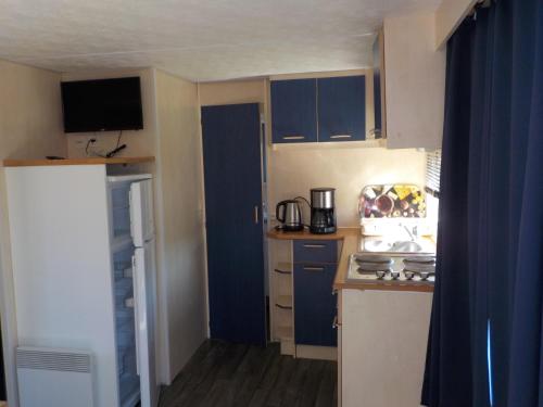 a small kitchen with blue cabinets and a stove at Village Vacances Les Sables d'Or in Gouville-sur-Mer