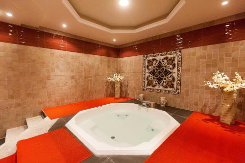 Red Castle Hotel في الشارقة: حوض استحمام كبير في حمام به بلاط احمر