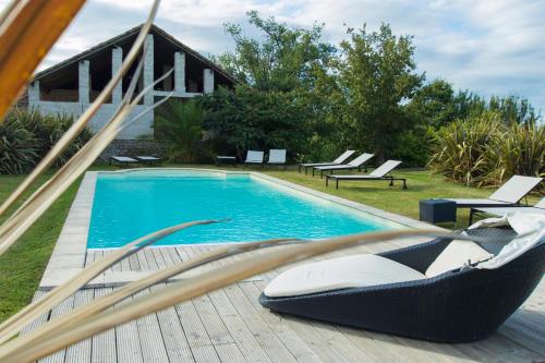a swimming pool with a hammock next to a house at Vintage Vert in Lahitte-Toupière