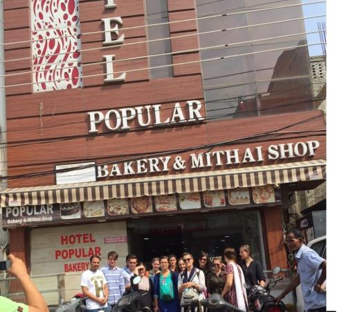 a group of people standing outside of a bakery and martial shop at Hotel Popular in Amritsar