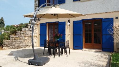 a table with an umbrella in front of a building at Au Doubs Cocon Fleuri in Mamirolle