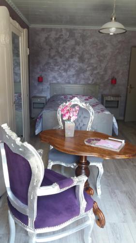 Au Doubs Cocon Fleuri في Mamirolle: غرفة مع طاولة وكراسي وسرير
