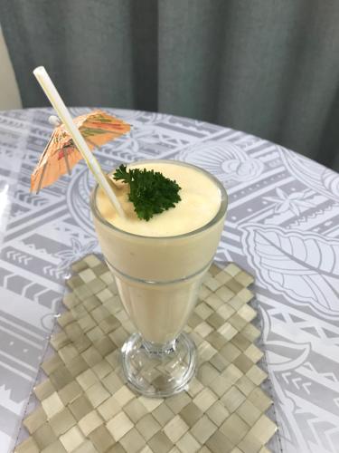 a drink in a bowl on a table with an umbrella at Moatoga Hotel in Apia