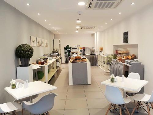 a restaurant with white tables and chairs in a room at Elite Hotel in Rhodes Town