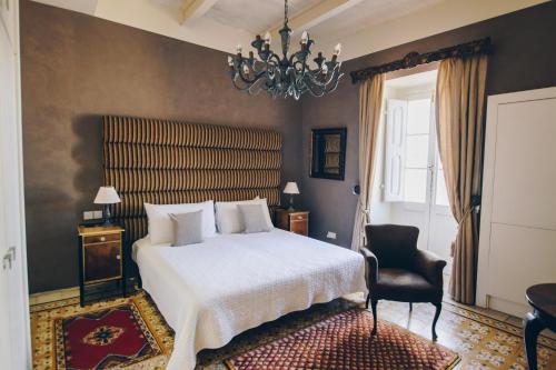um quarto com uma cama, uma cadeira e um lustre em Sally Port Senglea em Senglea