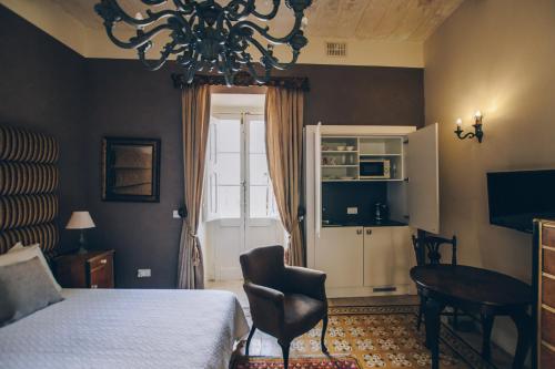 ein Schlafzimmer mit einem Bett, einem Tisch und einem Kronleuchter in der Unterkunft Sally Port Senglea in Senglea