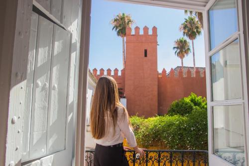 een vrouw die uit een raam naar een kasteel kijkt bij Apartamentos Boutique Vida in Sevilla