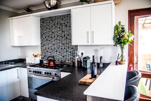 a kitchen with black counter tops and white cabinets at 16 On Antrim in Hermanus