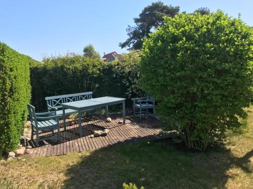 a bench sitting on a wooden deck next to a bush at Ferienwohnung Fritzi in Glowe