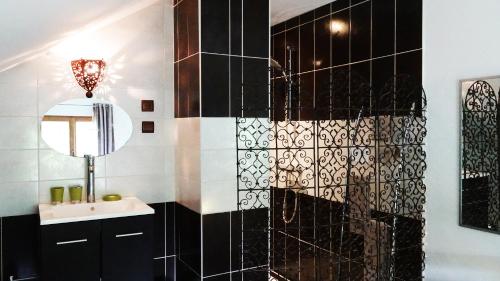 a black and white bathroom with a sink and a mirror at Le vieux Pressoir in Saint-Germain-lès-Arlay