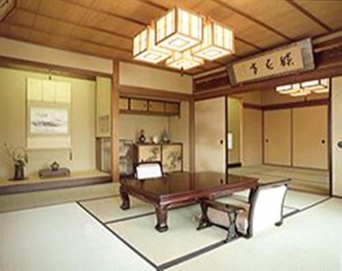 a dining room with a wooden table and a chandelier at Ise Todaya Ryoan in Ise