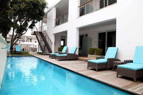 a swimming pool with chairs and a house at Hermanus Boutique Guest House in Hermanus