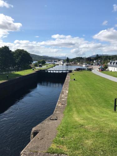a body of water with a grassy field next to it at Ramblers Rest Modern Cottage-Perfect Views of Ben Nevis in Fort William