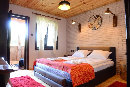 a bedroom with a large bed with a clock on the wall at Dream house in Leshten